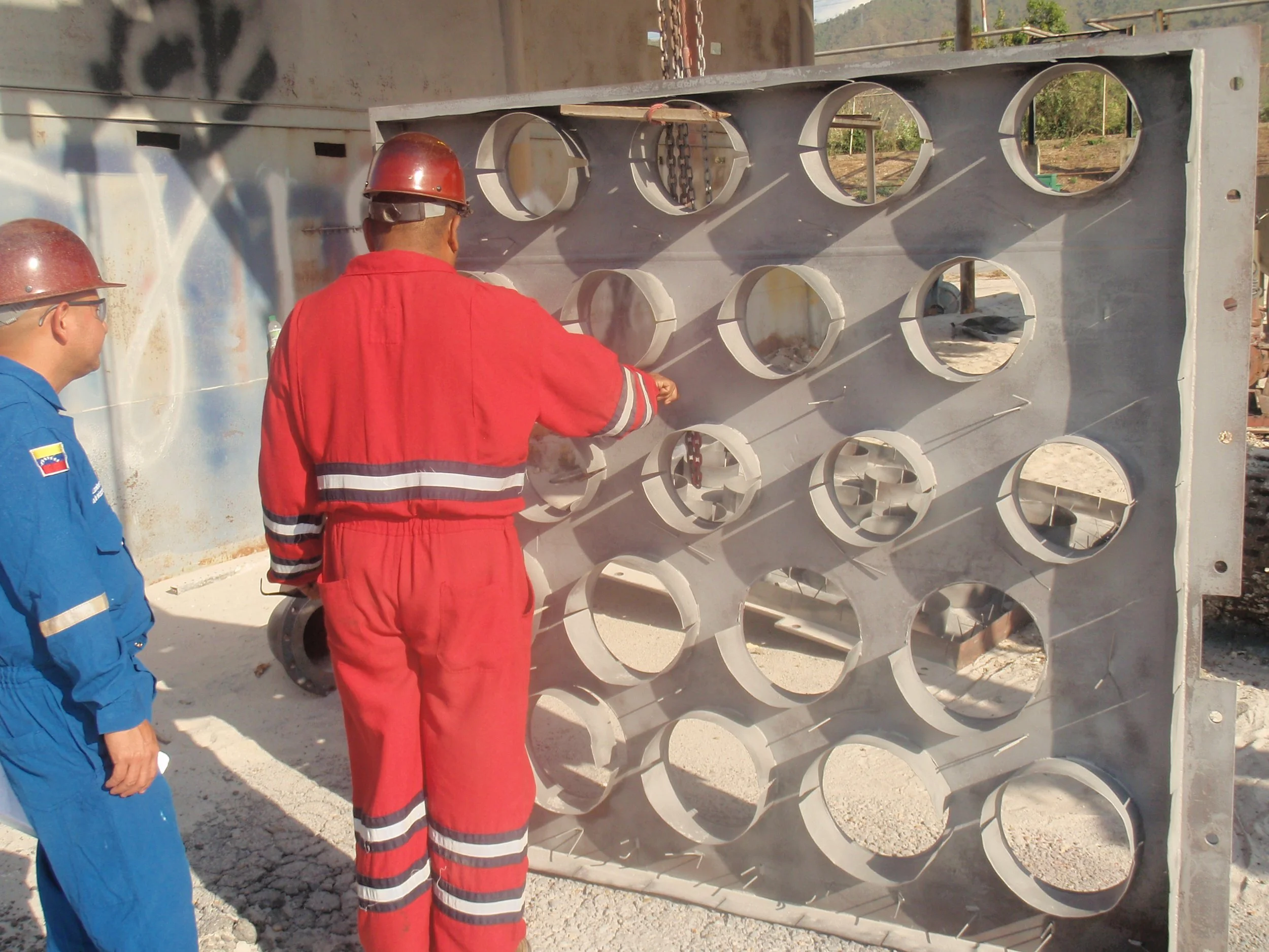 Dos trabajadores en uniforme de seguridad inspeccionan una gran estructura 