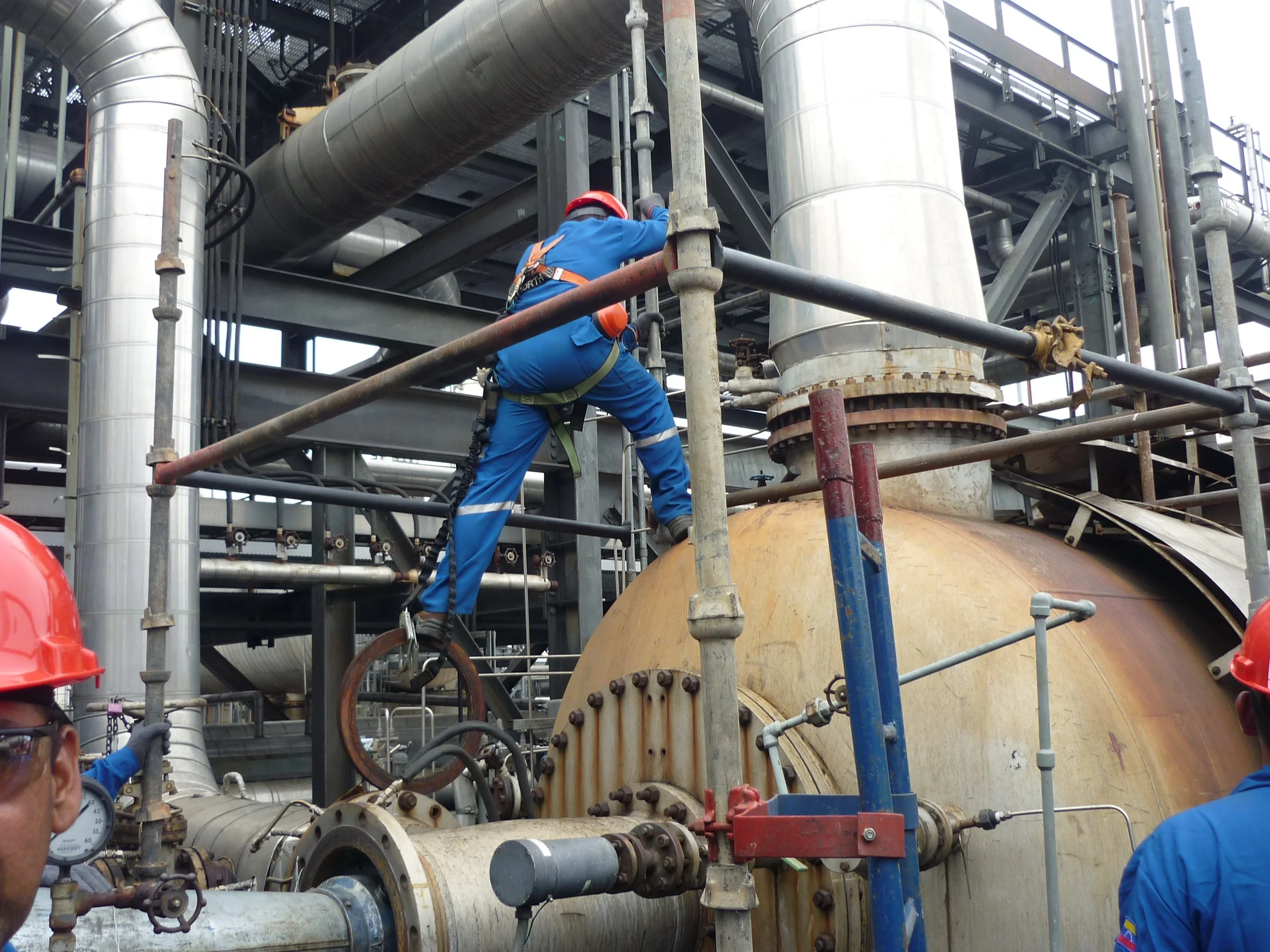 trabajadores en un entorno industrial, armando andamio en una refinería.