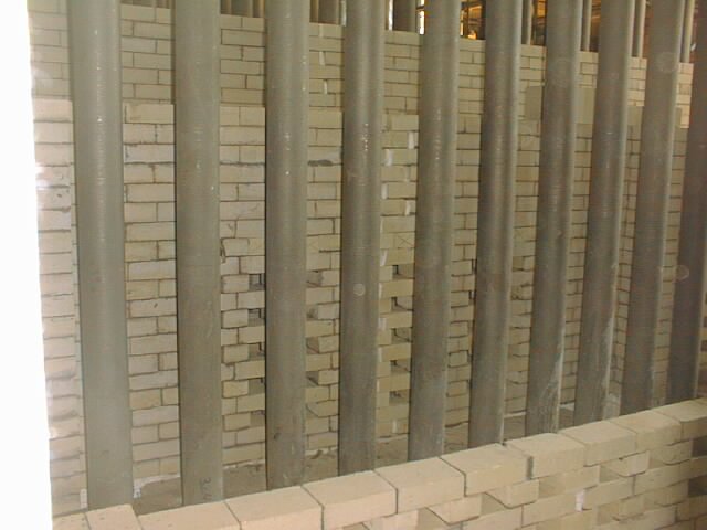 trabajador en pasillo con paredes de ladrillos, colocando ladrillos refractarios  