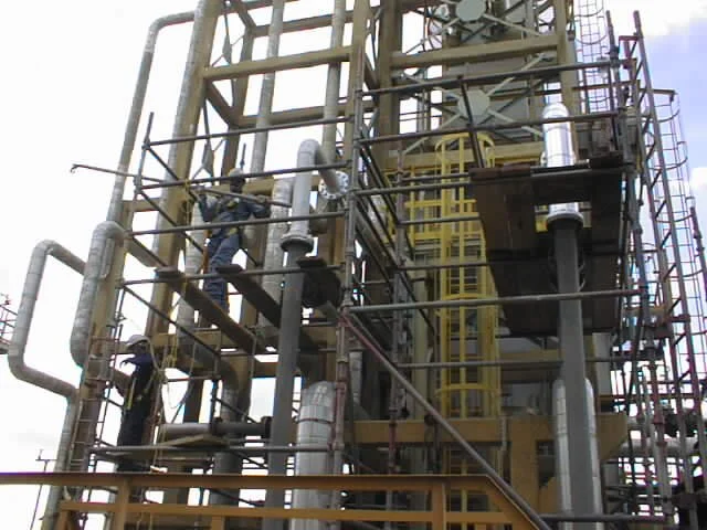 Una estructura industrial con tuberías, escaleras y trabajadores realizando mantenimiento.