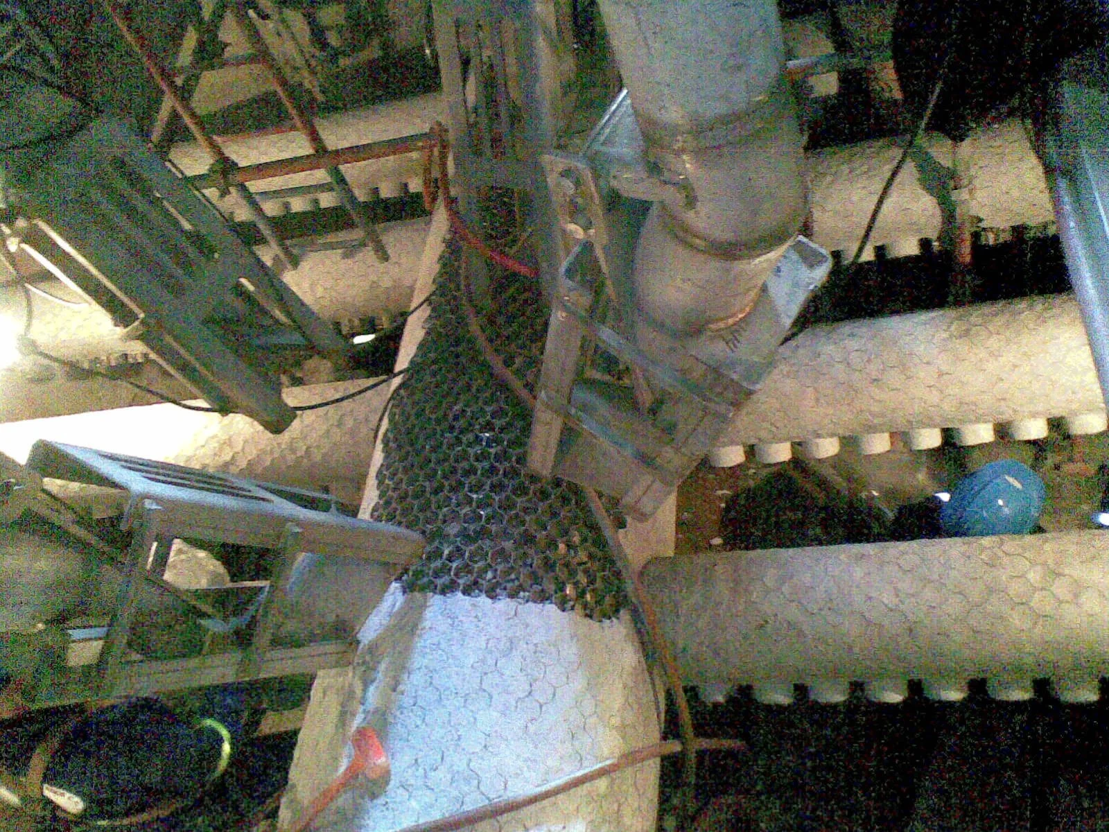 Mesas y sillas en un espacio cerrado, con objetos diversos y cables eléctricos sobre ellas, en un entorno de taller o almacenamiento.