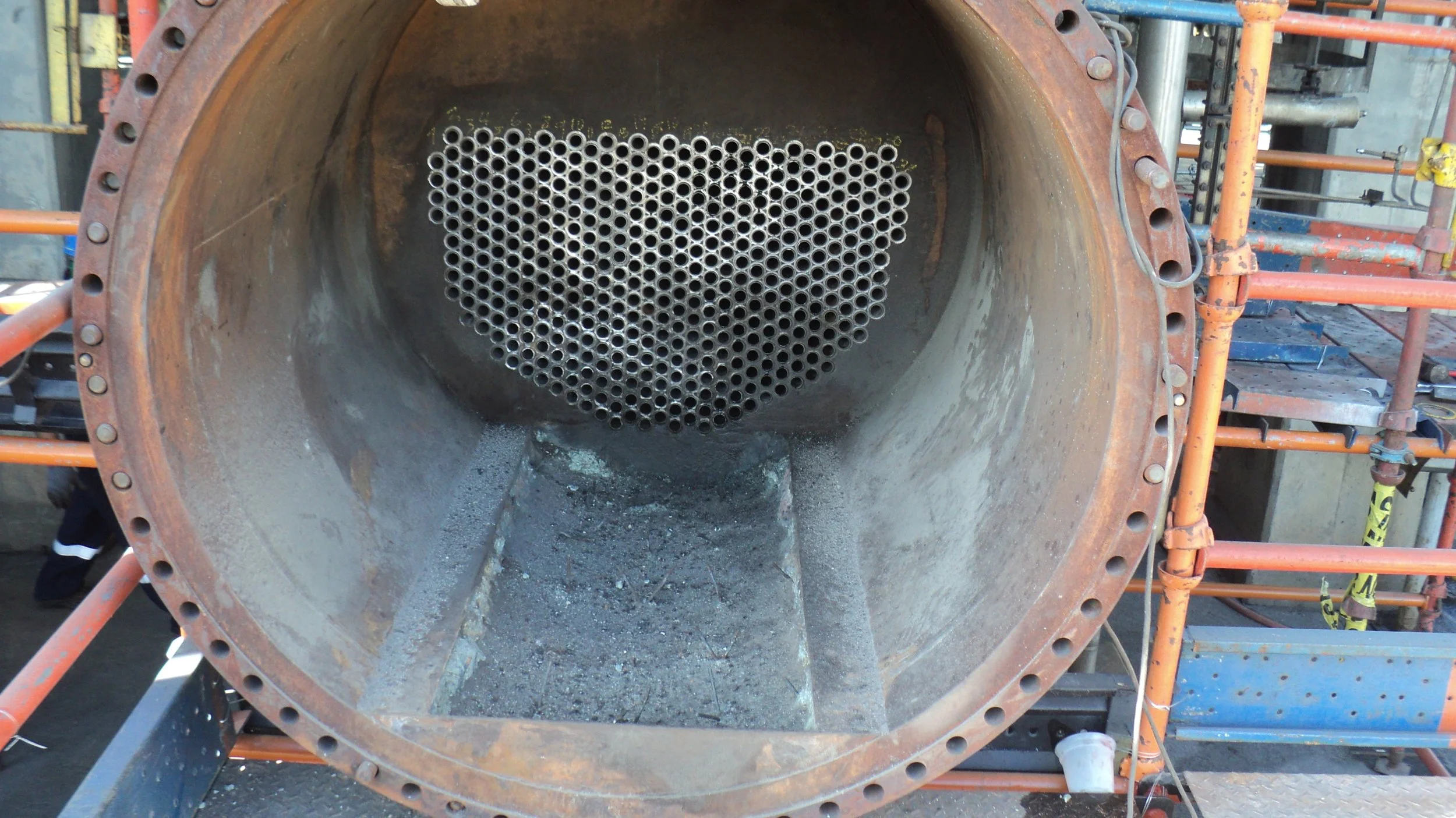 reentubado. Trabajador con equipo de protección utilizando una herramienta para intercambiador de calor .