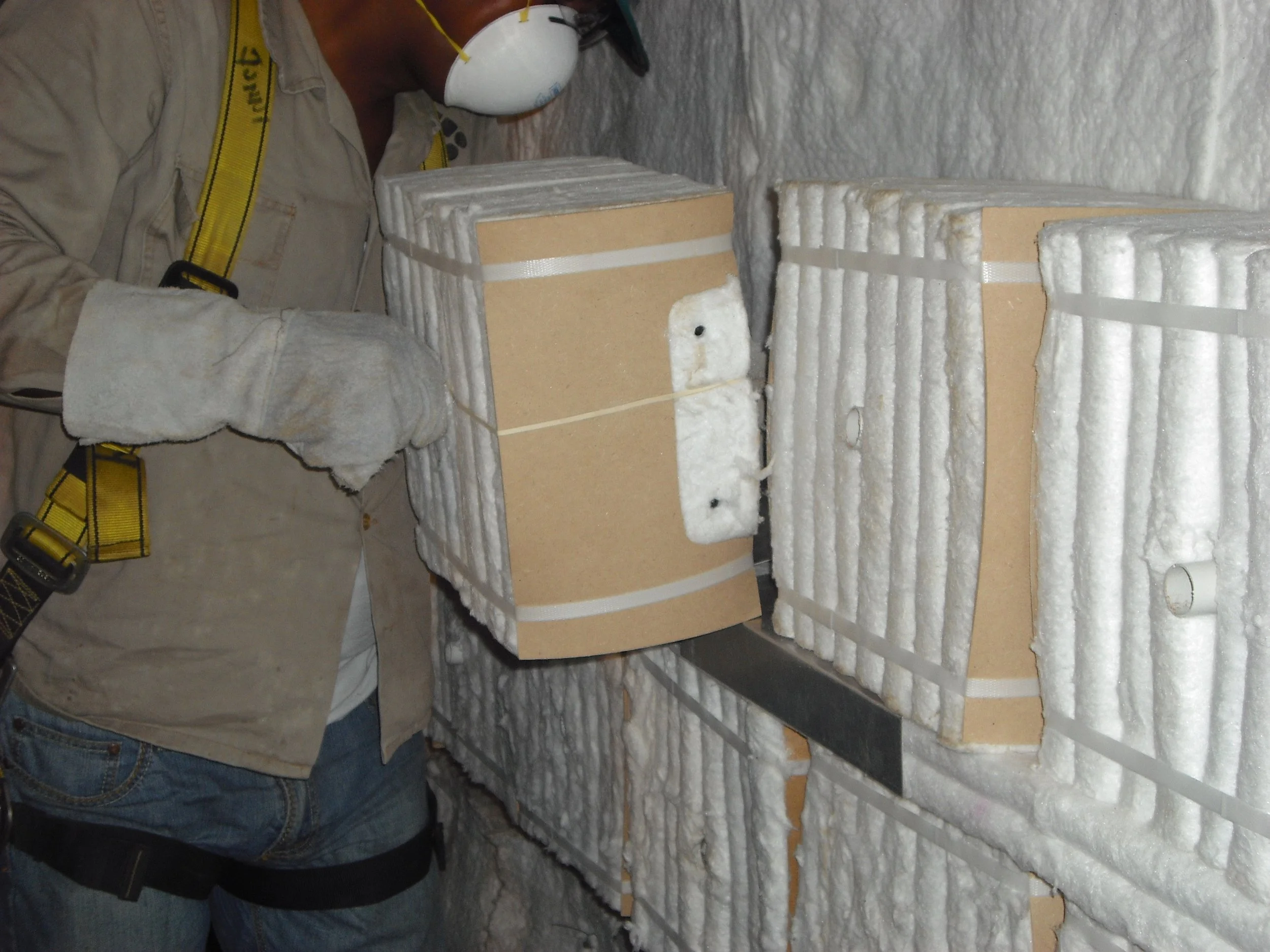 Trabajador con equipo de seguridad instalando fibra ceramico  en pared .