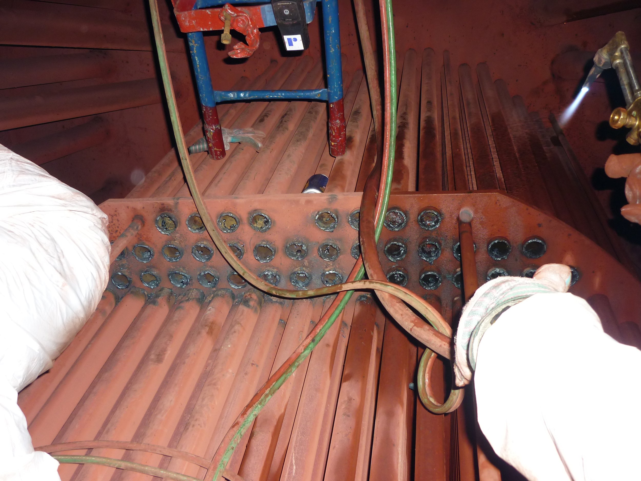 reentubado. Trabajador con equipo de protección utilizando una herramienta para intercambiador de calor .