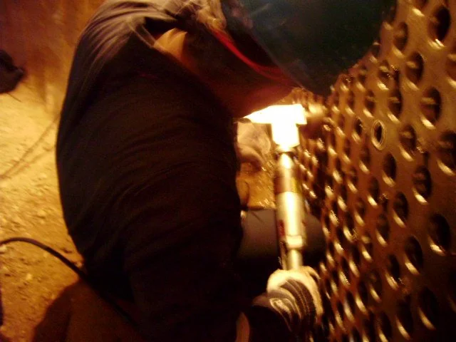 reentubado. Trabajador con equipo de protección utilizando una herramienta para intercambiador de calor .