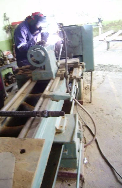 Persona trabajando con una máquina de soldar en un taller industrial.