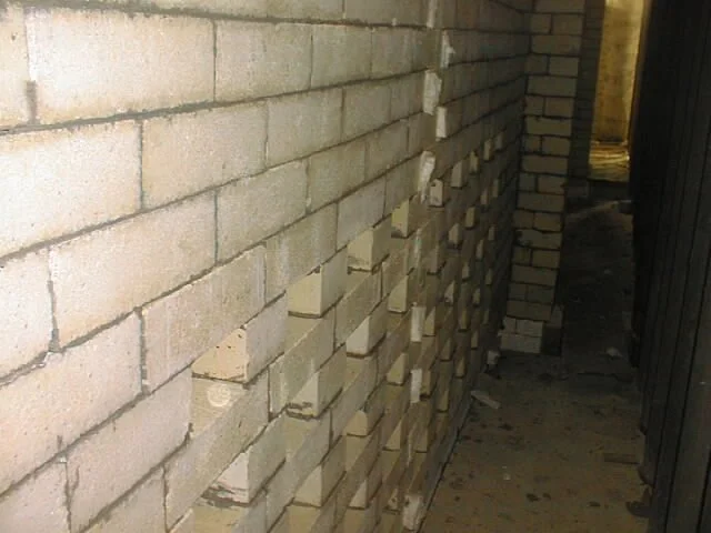 trabajador en pasillo con paredes de ladrillos, colocando ladrillos refractarios  