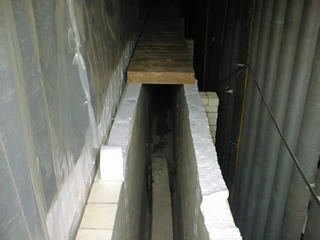 trabajador en pasillo con paredes de ladrillos, colocando ladrillos refractarios  