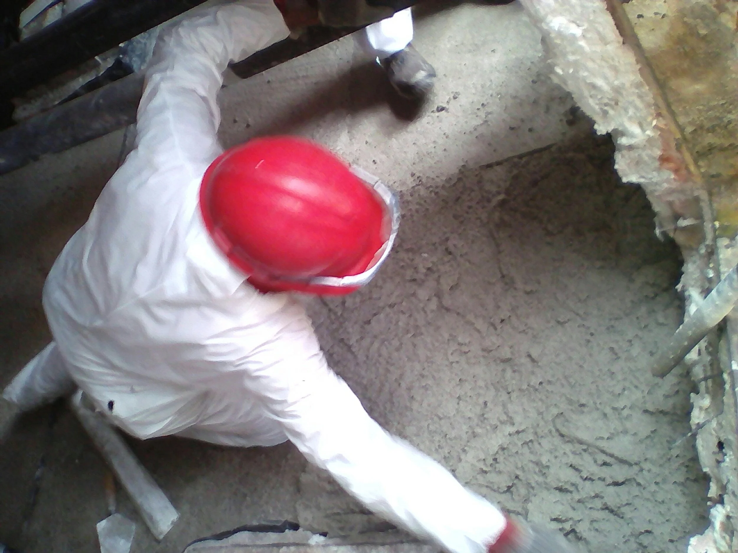 Persona con guantes colocando cemento en un muro de construcción.