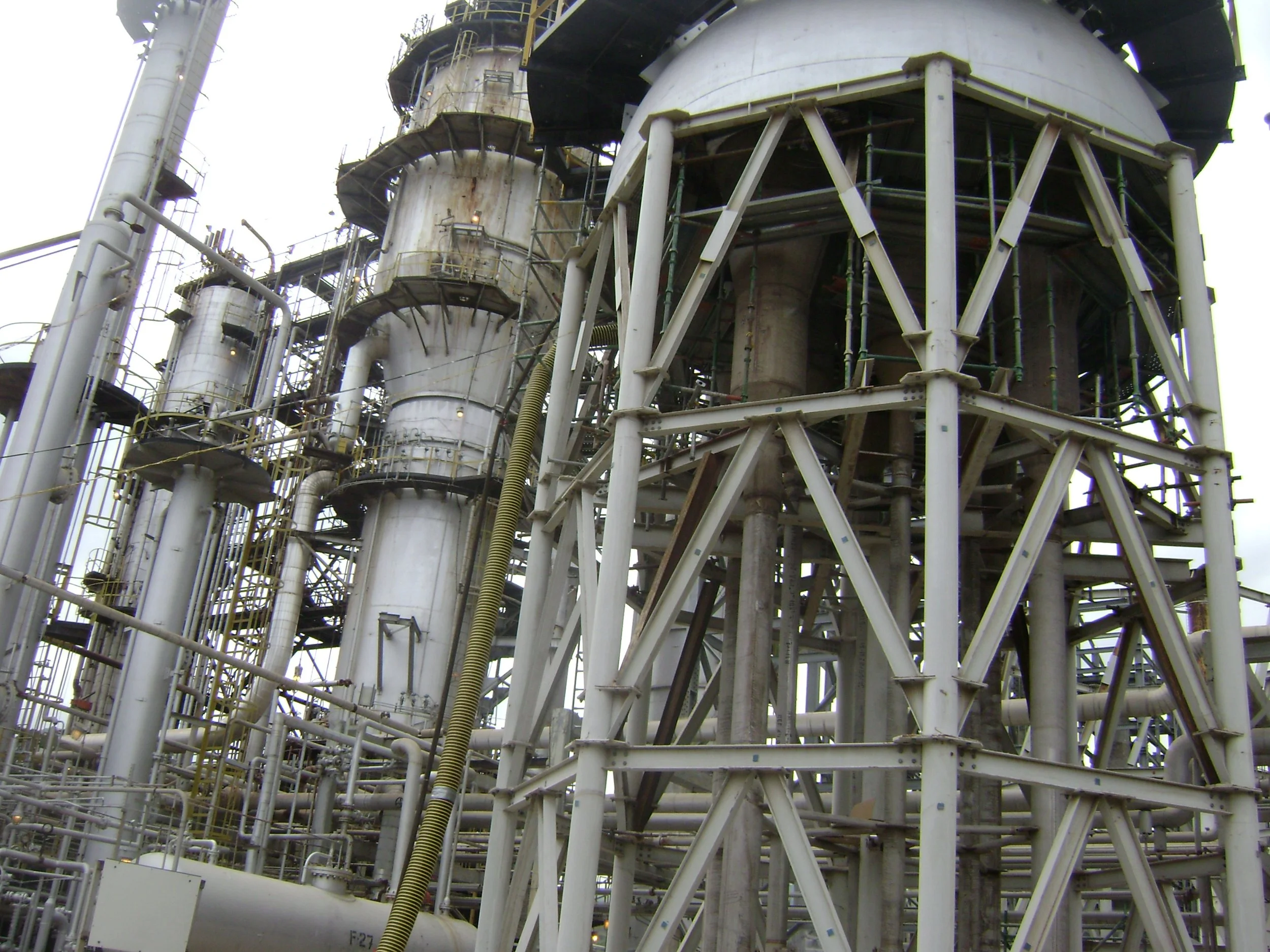 Estructuras metálicas de una planta industrial con tuberías y tanques grandes.