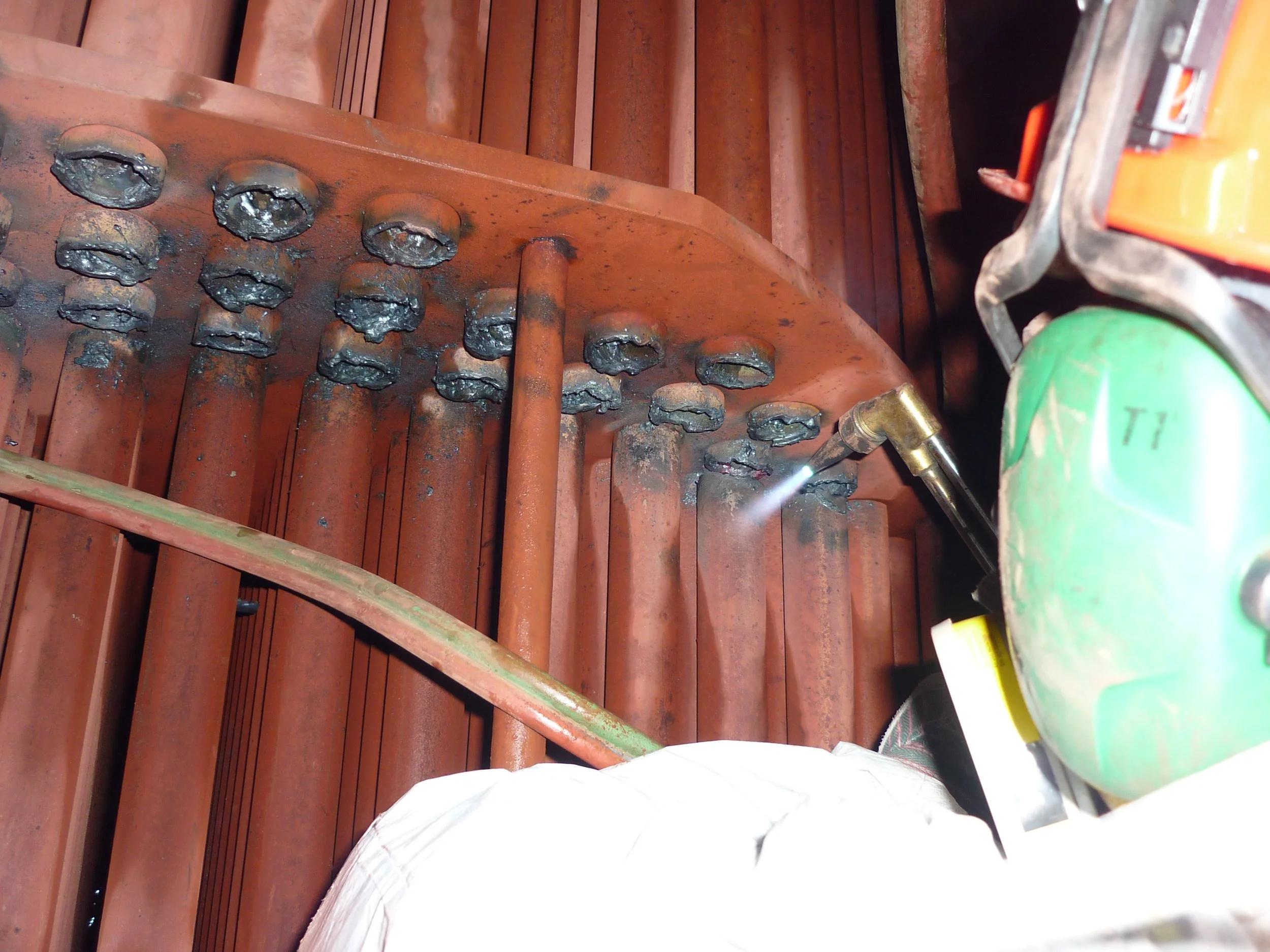 reentubado. Trabajador con equipo de protección utilizando una herramienta para intercambiador de calor .Soldador soldando una estructura de acero, 