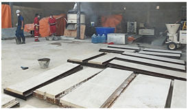 Mesas de piedra apiladas en un taller con herramientas y personas trabajando.