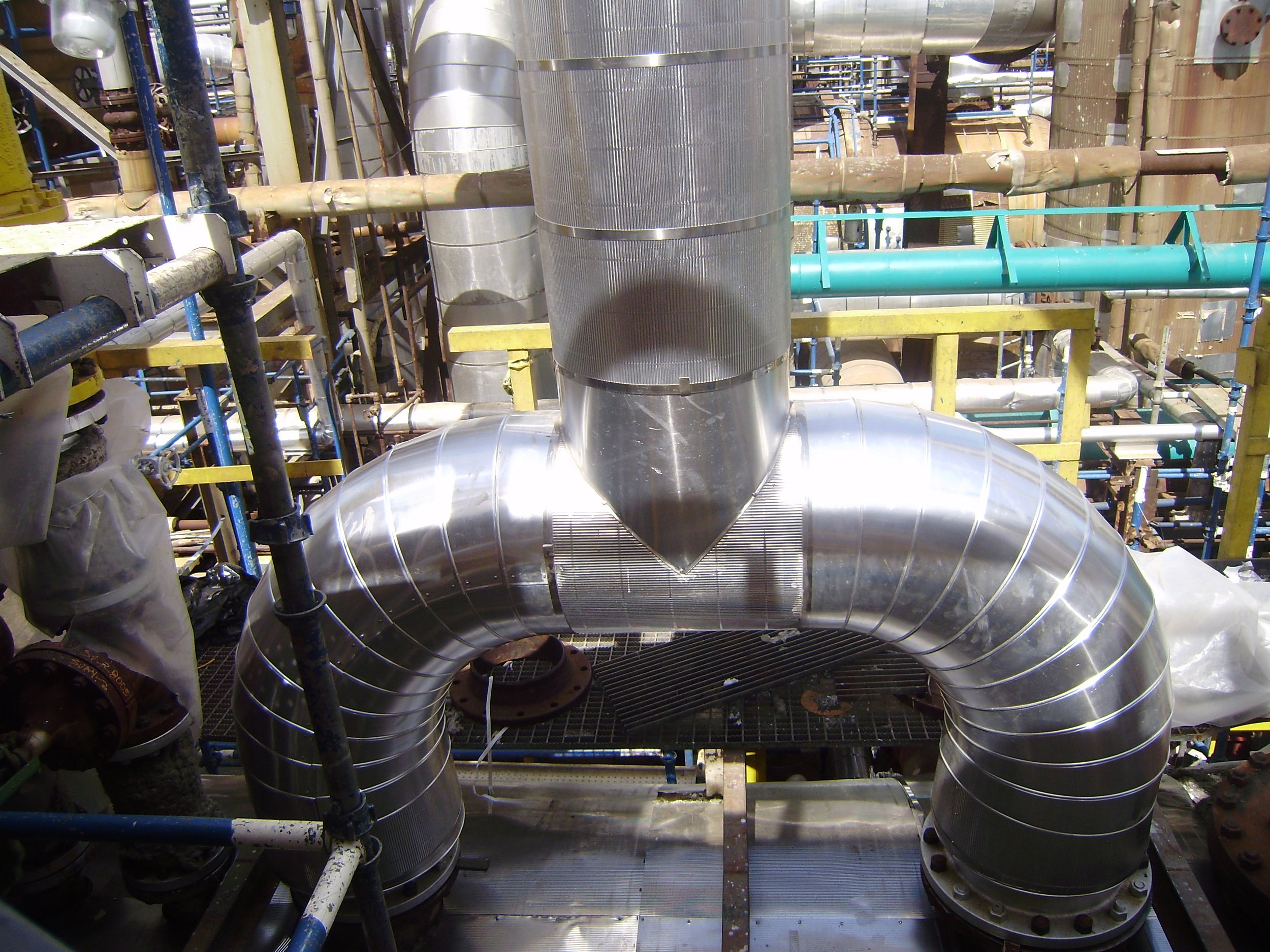 Conductos de ventilación de acero inoxidable dentro de una planta industrial.