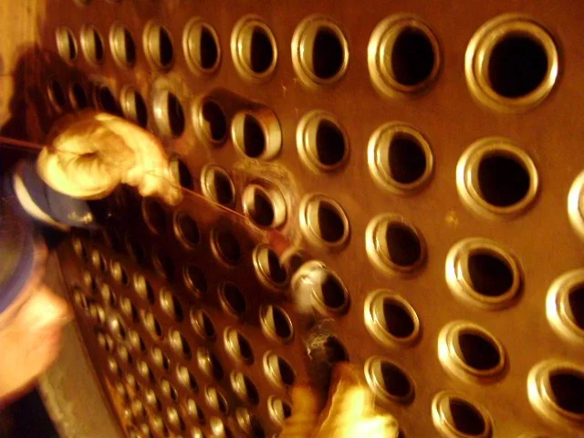 Persona trabajando reentubado de un intercambiador de calor.