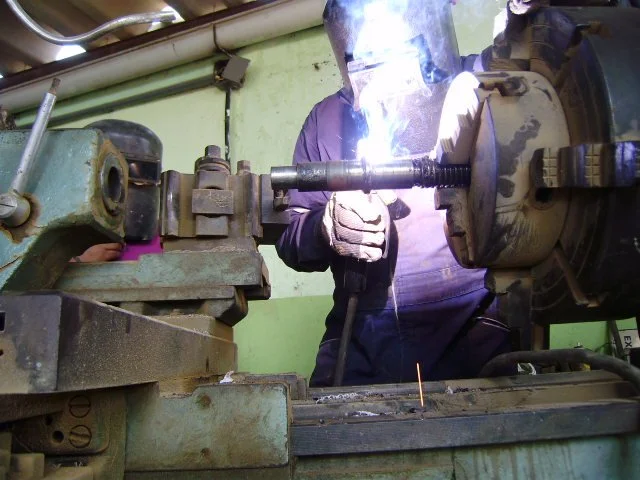 Trabajador soldando una pieza de metal en un taller.