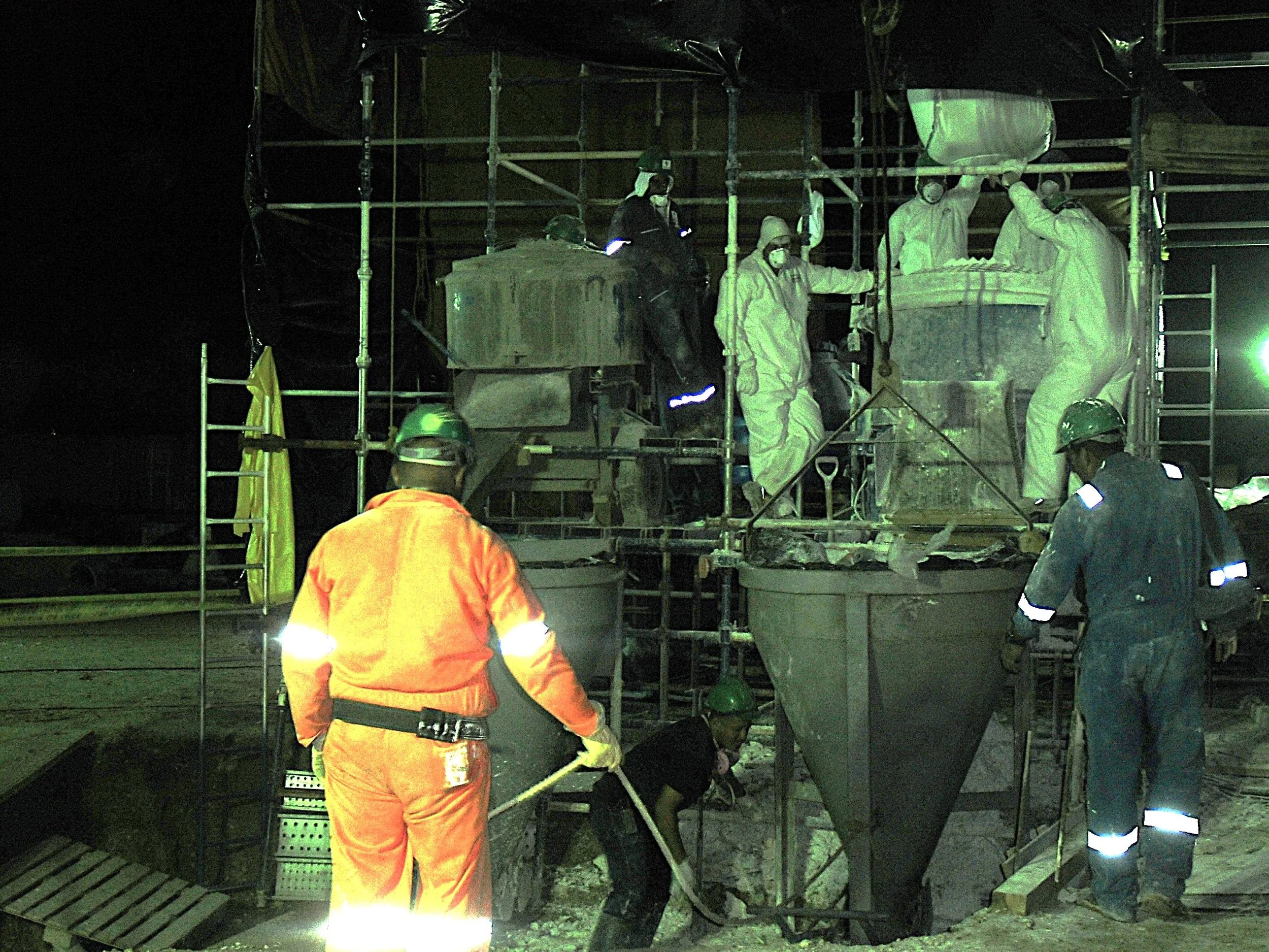 vaciado de reformador secundario. Trabajadores en una obra de construcción usando equipo de protección en medio de la noche.