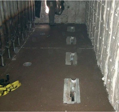 Vista de una construcción o instalación con raíles en el suelo y paredes de cemento.