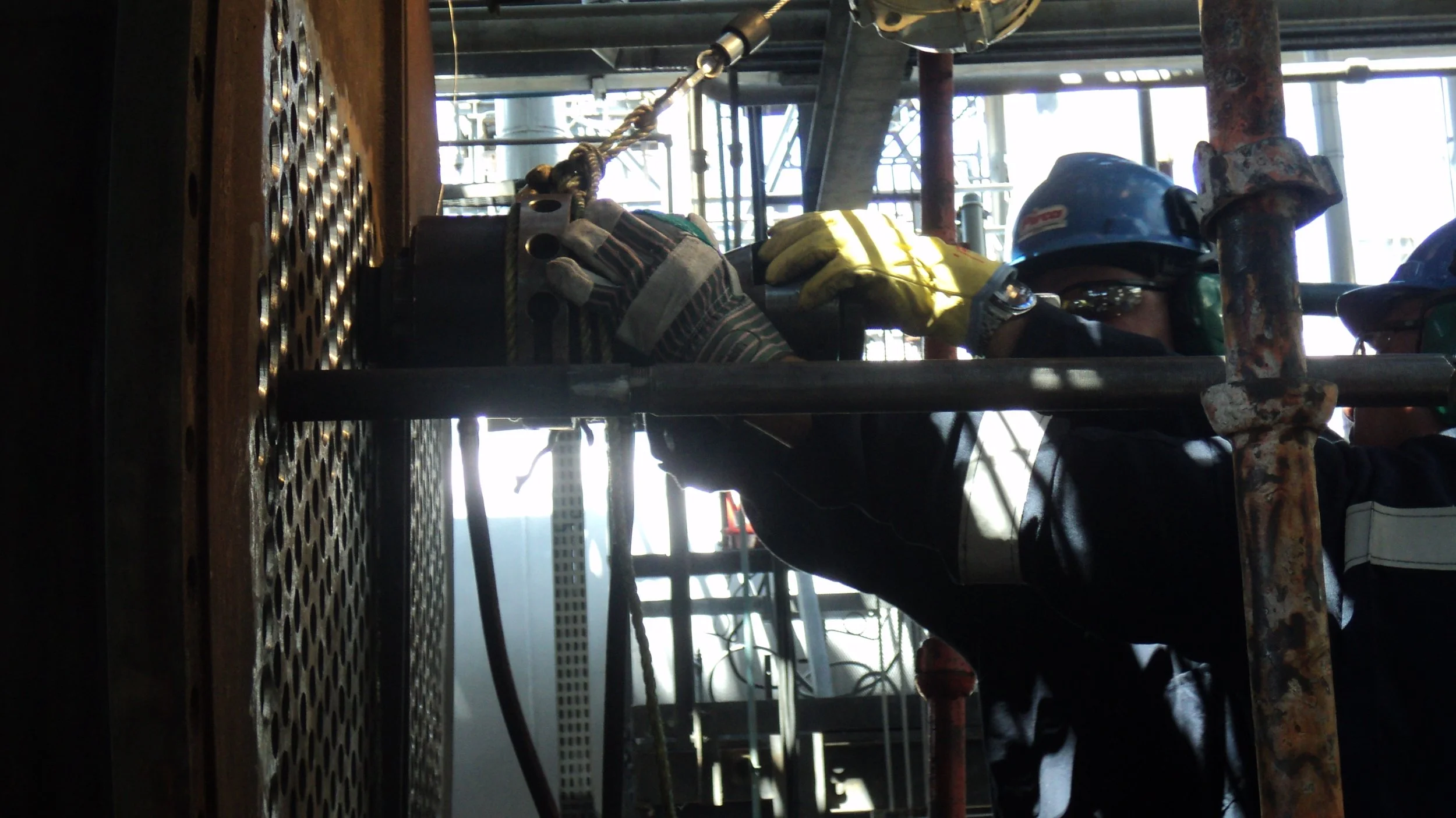 reentubado. Trabajador con equipo de protección utilizando una herramienta para intercambiador de calor .