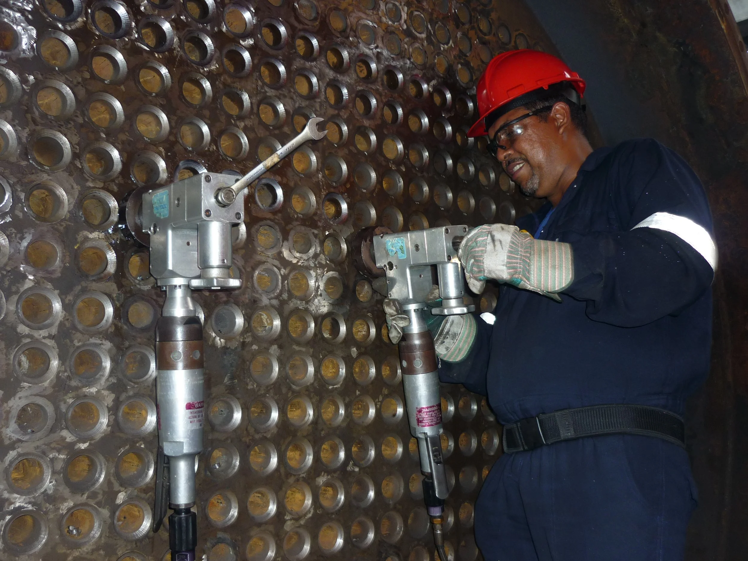 reentubado. Trabajador con equipo de protección utilizando una herramienta para intercambiador de calor .