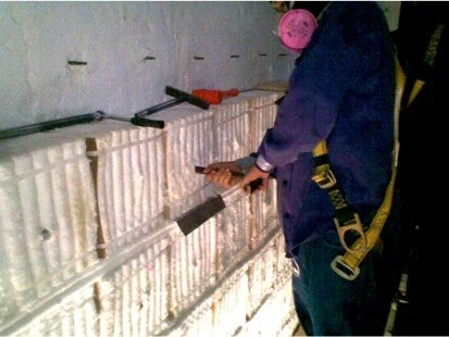 Persona instalando fibra ceramica con herramientas en una pared 