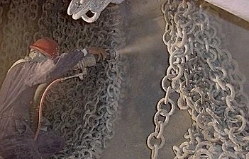 Trabajador proyectando material refractario en cadenas de metal horno cementera.