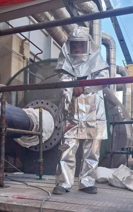 Persona usando traje de protección, Persona con casco en una planta industrial operando equipo portatil de secado dryout.