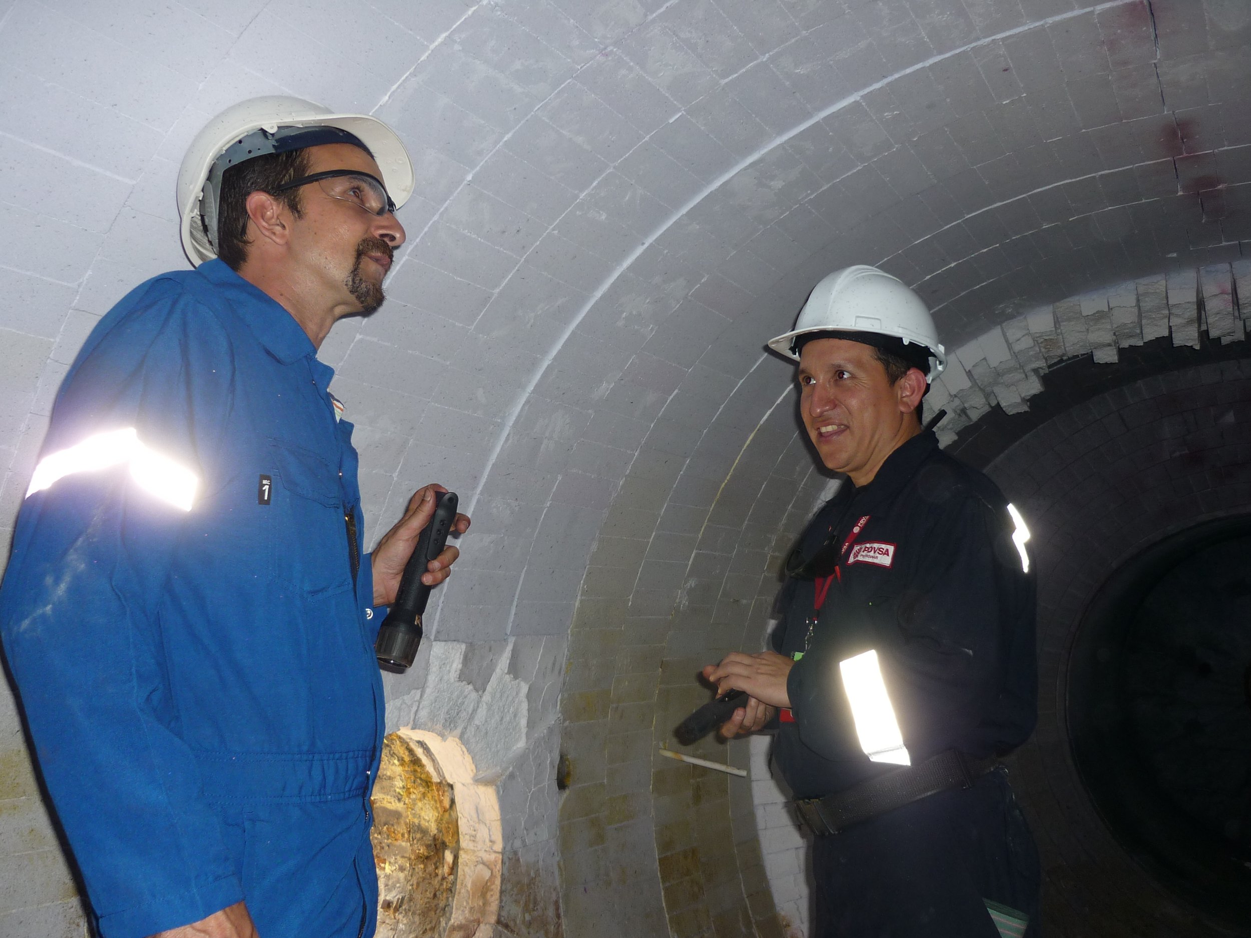 Horno clauss. Dos hombres con cascos de seguridad. Uno lleva una linterna y el otro una radio.