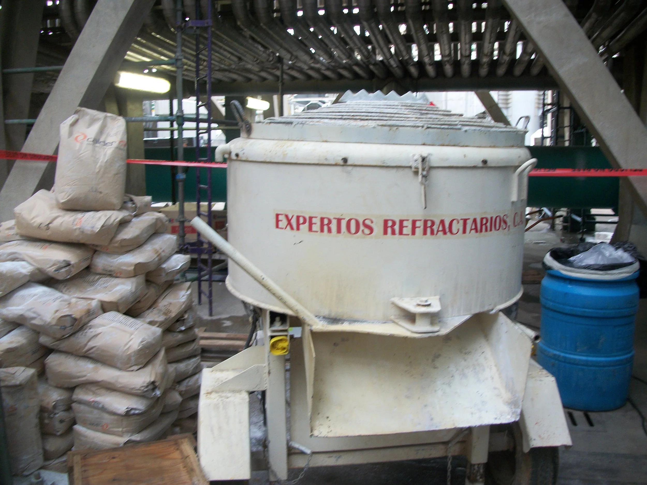 Mezcladora en una obra, con bolsas de material apiladas a su lado.