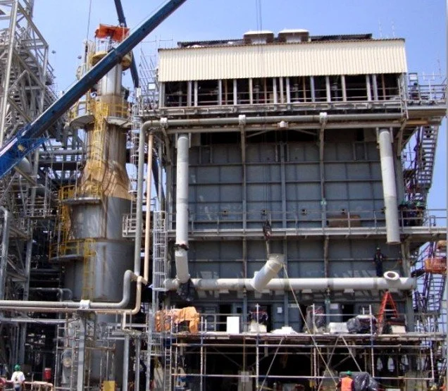 Infraestructura industrial en construcción, con tuberías, plataformas y maquinaria.