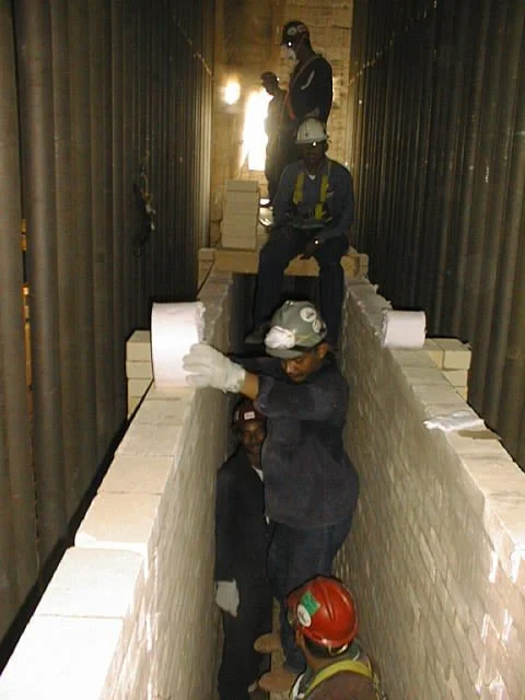trabajador en pasillo con paredes de ladrillos, colocando ladrillos refractarios  