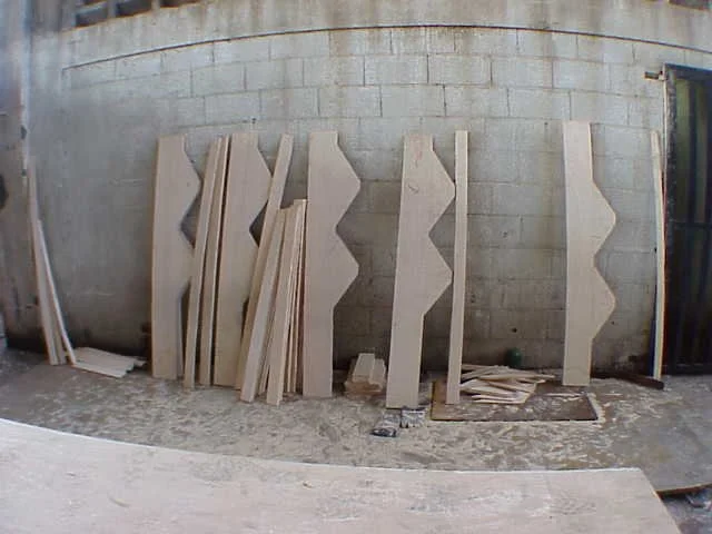 madera cortadas y apiladas en un taller junto a una pared de bloques de cemento.