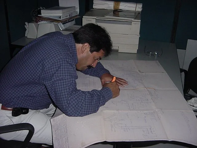 Hombre trabajando en planos  sobre una mesa en oficina