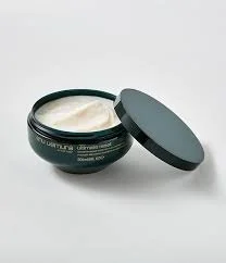 Open jar of white cream with black lid beside it on white surface.