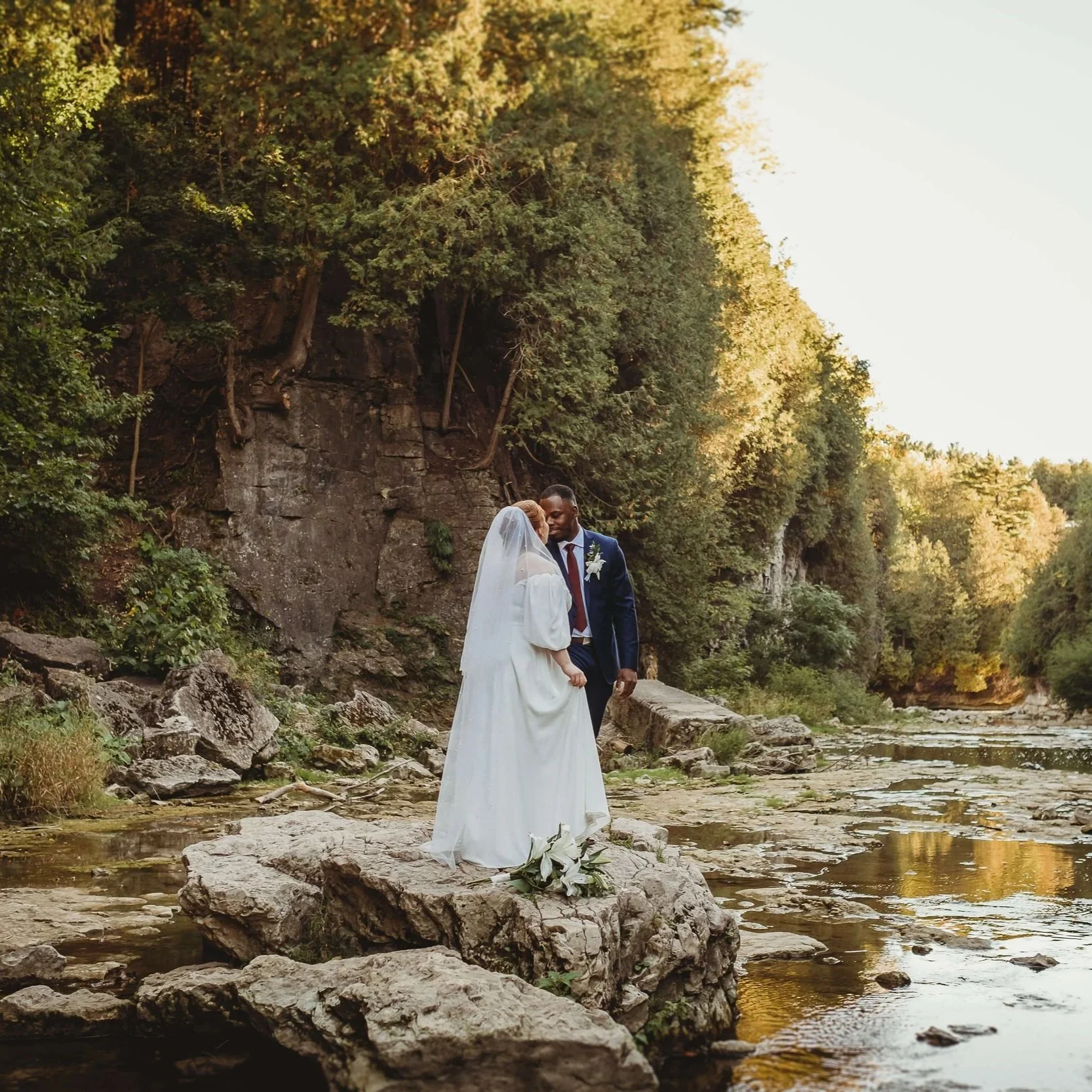 wedding elopement in Elora Gorge, Ontario. bride and groom standing on a rock by the water