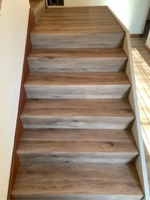 Wooden staircase with six steps, tan walls on sides, and a wooden floor at the bottom.