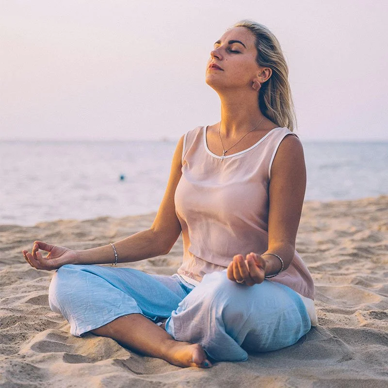 woman meditating on the beach