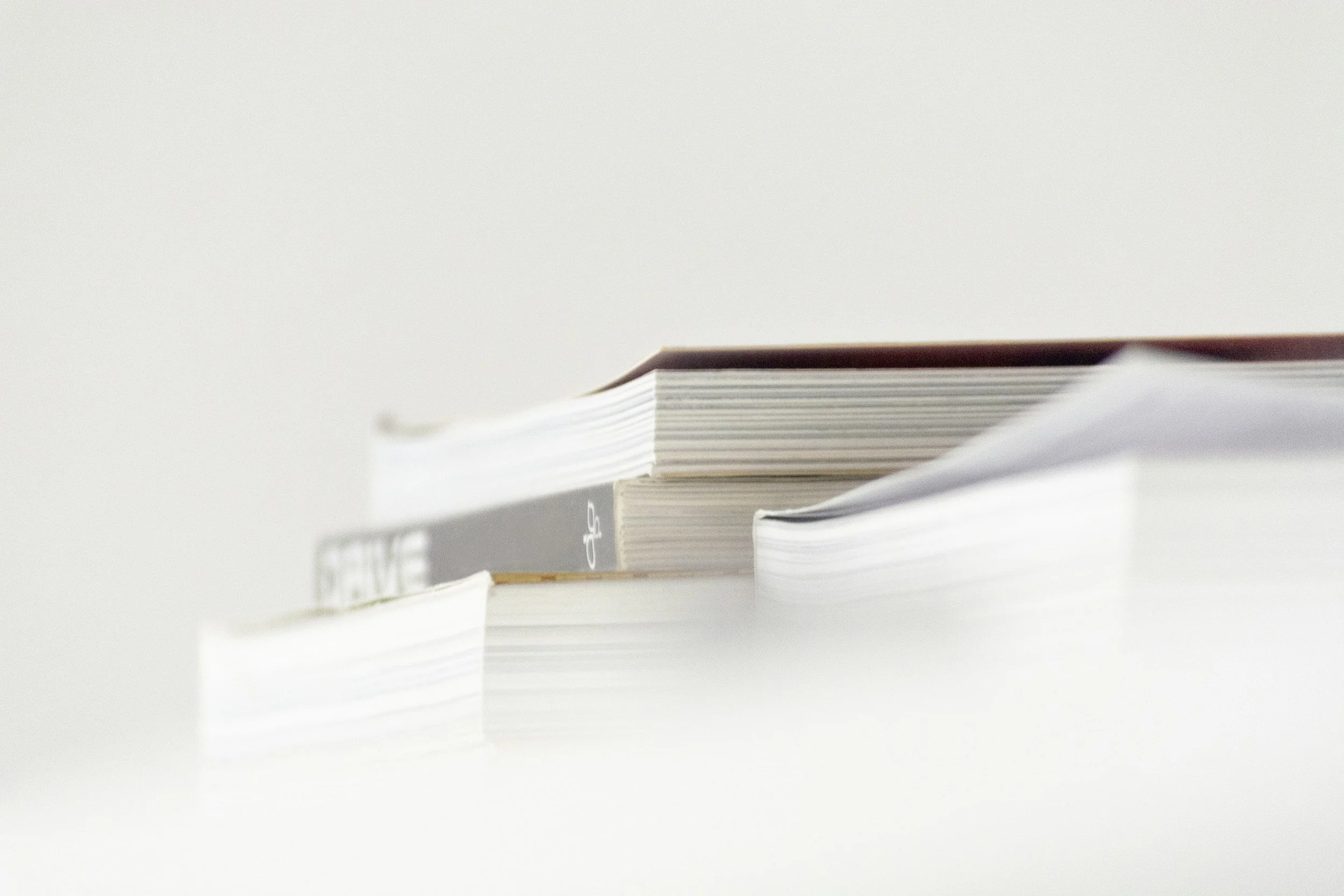 Close-up of stacked notebooks and papers on a white surface