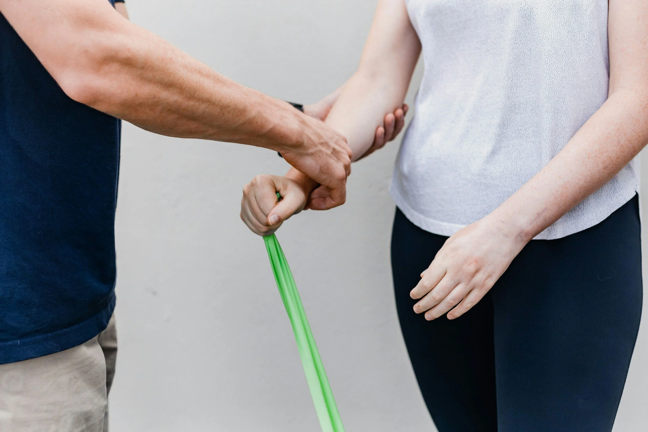 A person is holding a child's hand, with one of the child's hands gripping a green glow-in-the-dark stick while the adult is holding the child's hand gently.