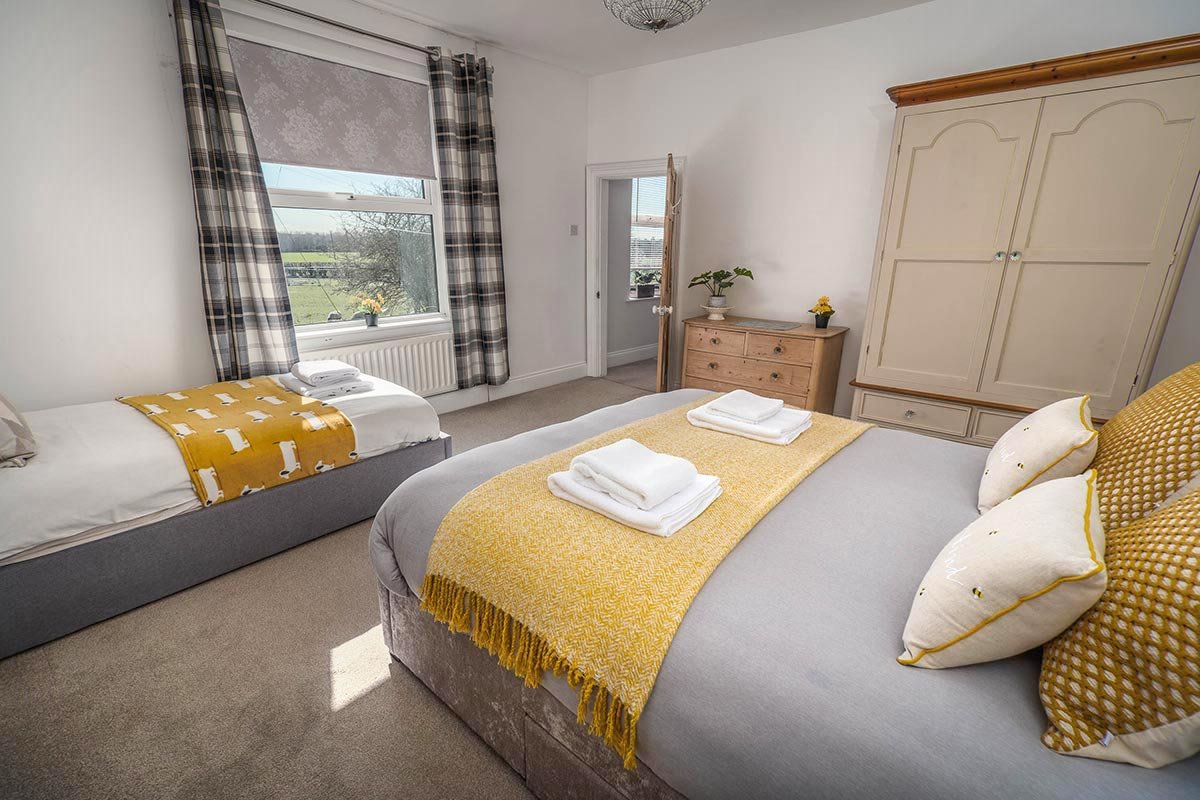 Clayfield Farmhouse bedroom with one double bed and one single bed, wardrobe and chest of drawers