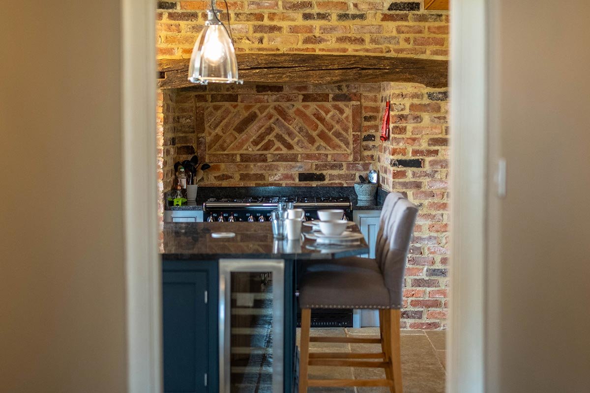 Clayfield Farmhouse kitchen with exposed brick wall, wine fridge and breakfast bar