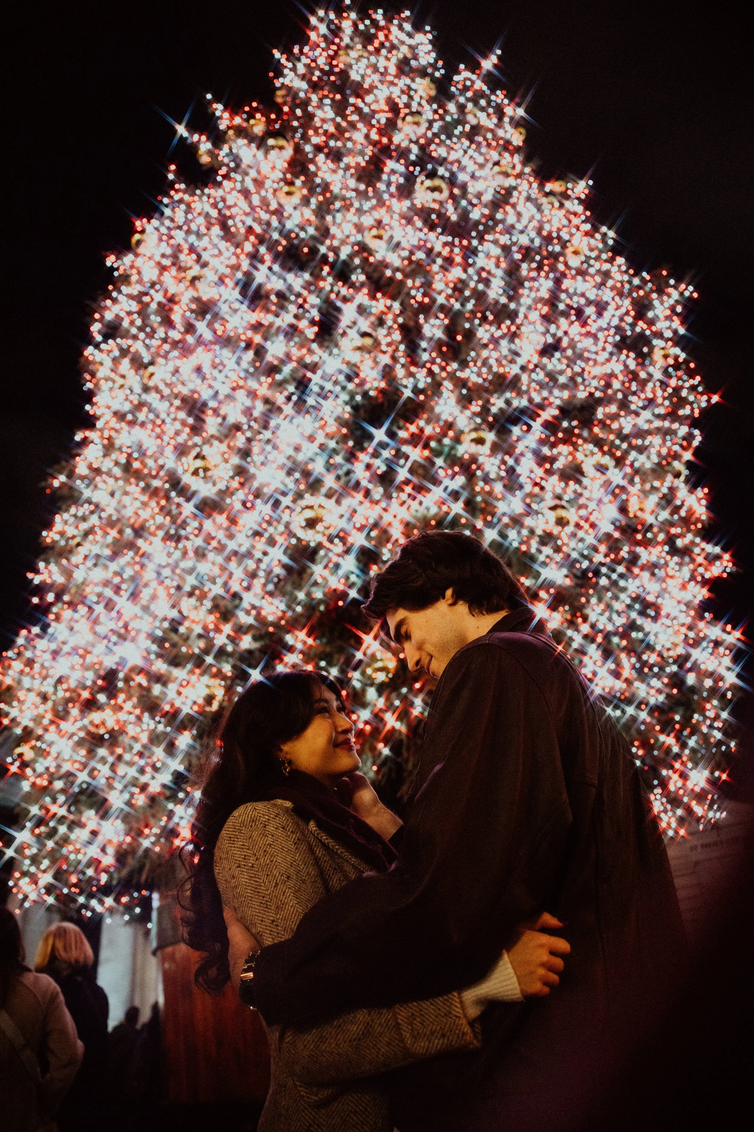  christmas tree sparkling behind couple embracing 