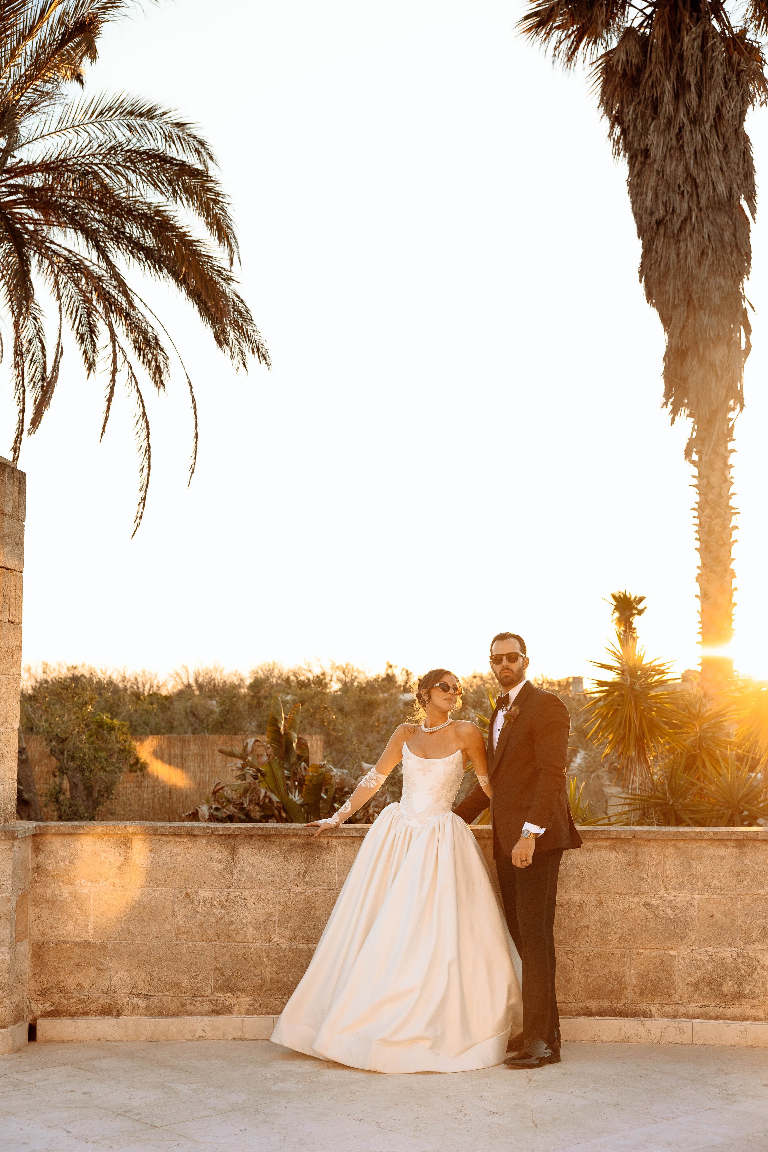 Rosalinda and Matt lean against the stone at Masseria Quadrelli under the setting sun