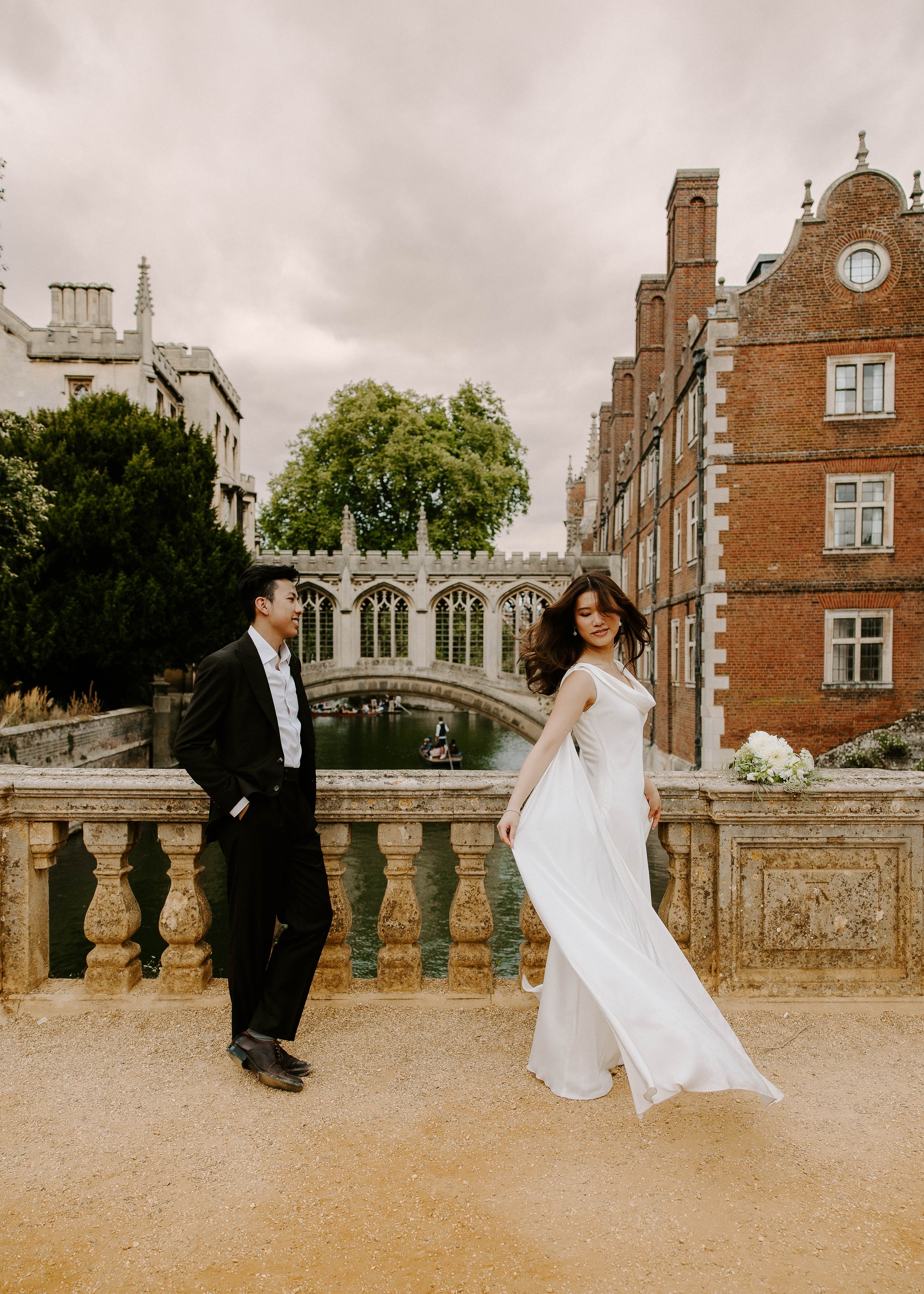 Candace twirls her dress while standing next to Justice with a beautiful bridge in the background