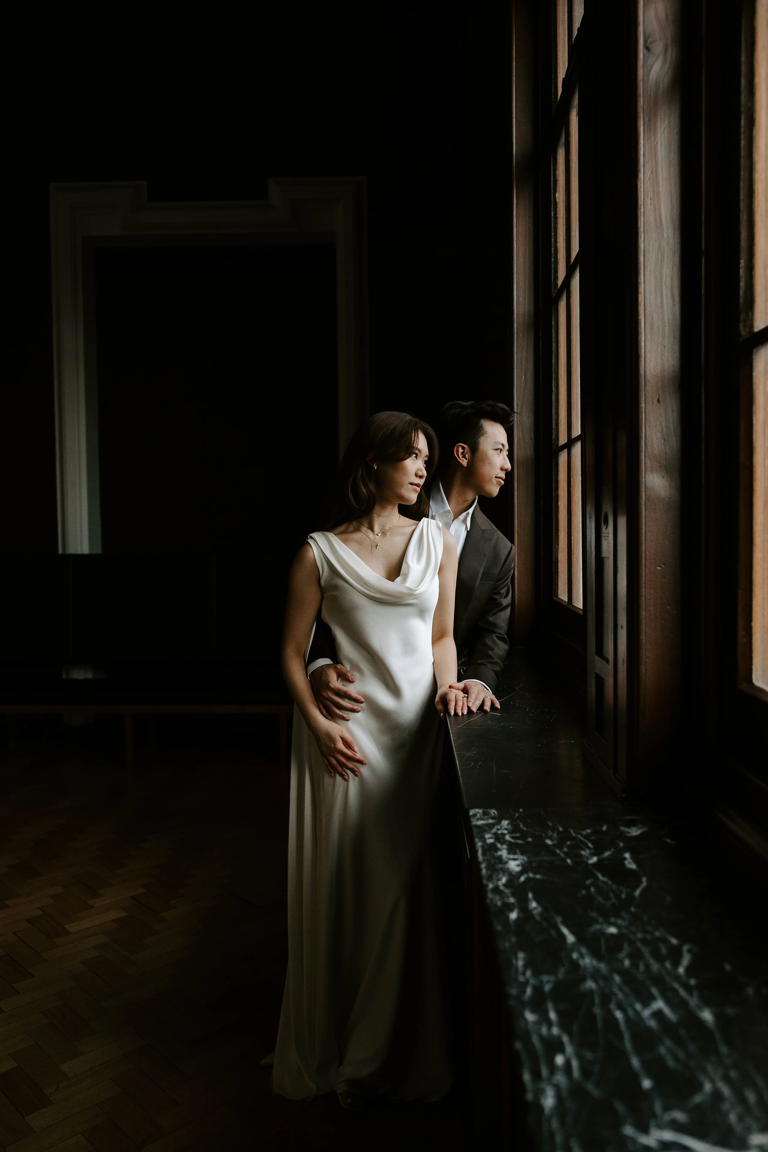 Justice and Candace lean against a window in a dark room of the museum
