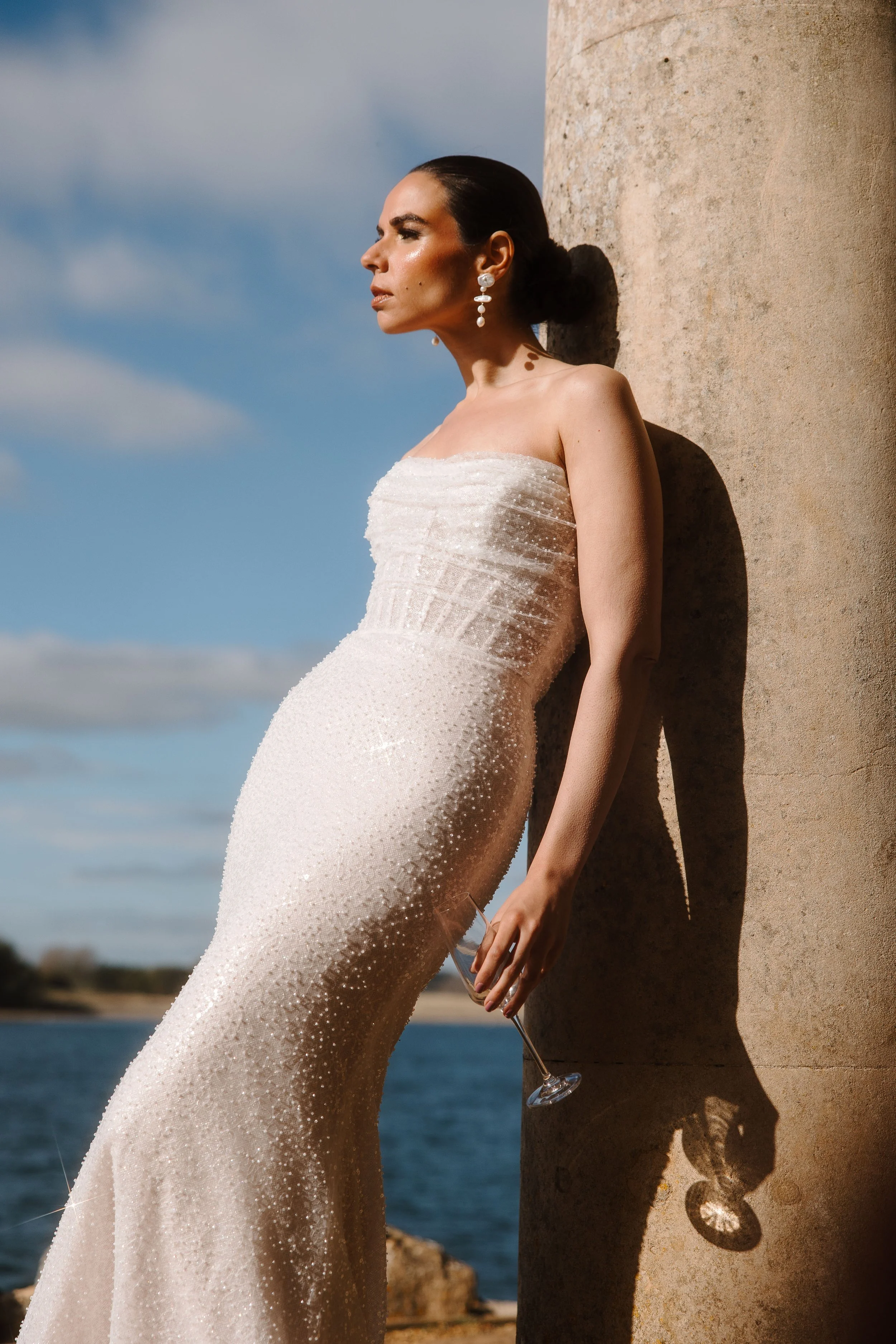Bride leaning on column holding glass