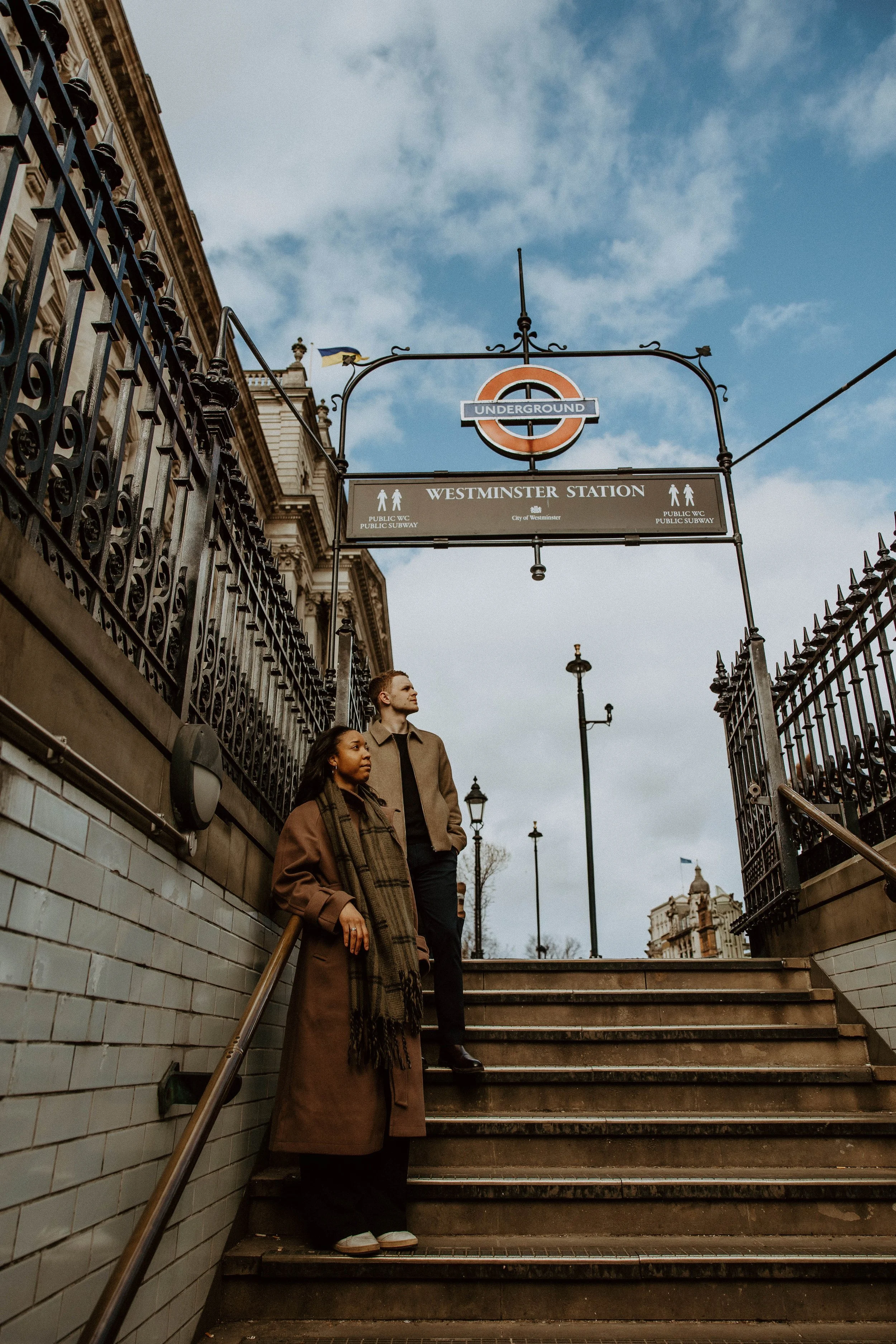 Amira and Caleb on the stairs to the Westminster station underground entrance