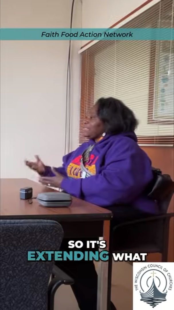 Near the top of the image, a narrow teal band contains thin, black, italicized text reading, “Faith Food Action Network.” An African American woman in a purple sweatshirt with a red and yellow design on the front is seated at a table, speaking, and g