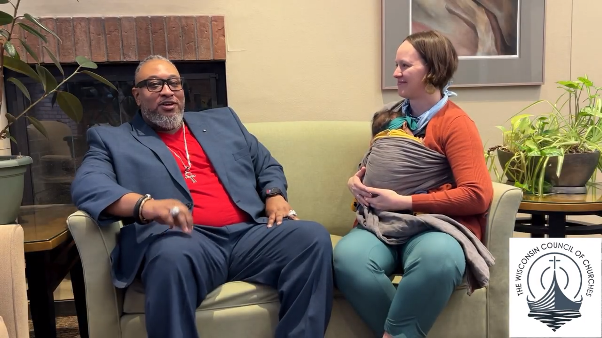 Mr. Eyon Biddle Sr and Rev. Breanna Illéné sit on a sofa, near a fireplace and tables with potted plants. Rev. Illéné is holding her infant daughter. The logo for Wisconsin Council of Churches is in the lower right corner.