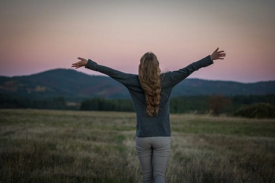 a woman at sunset with arms open