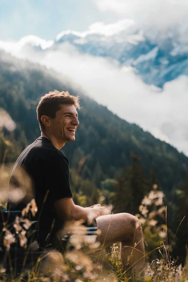 A man smiling outside in the mountains